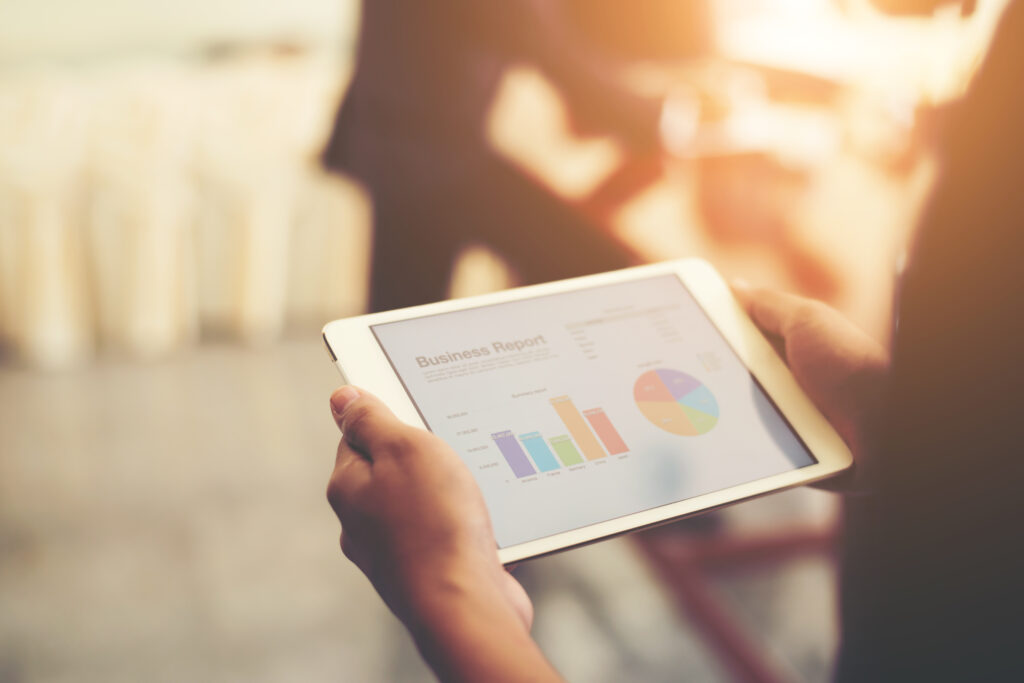 Business person hand holding financial statistics displayed on t